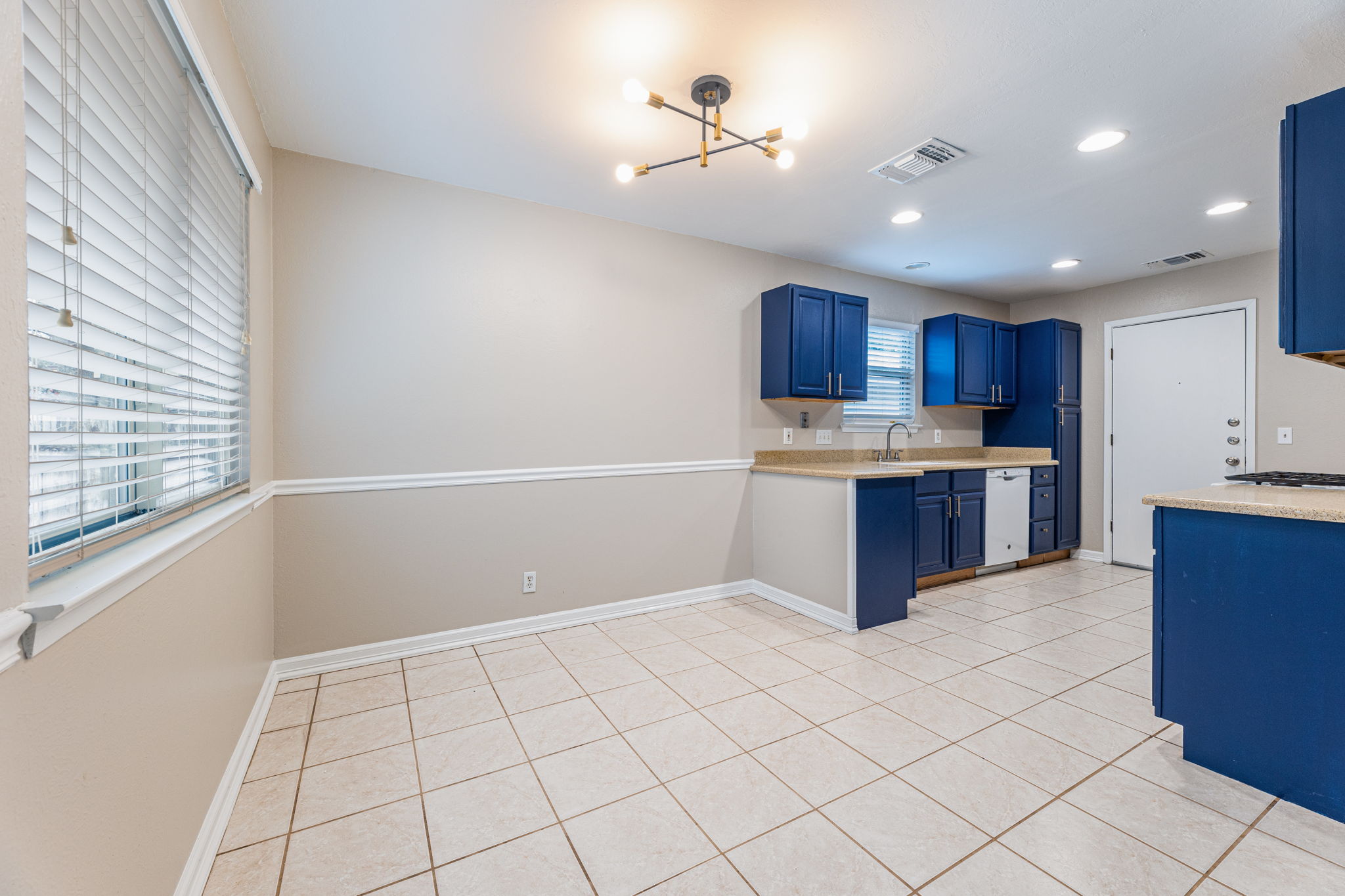 12914 Pegasus Street Austin, TX 78727 - Photo 8 of 30 Kitchen with blue cabinetry, light tile patterned flooring, dishwasher, and suspended lighting