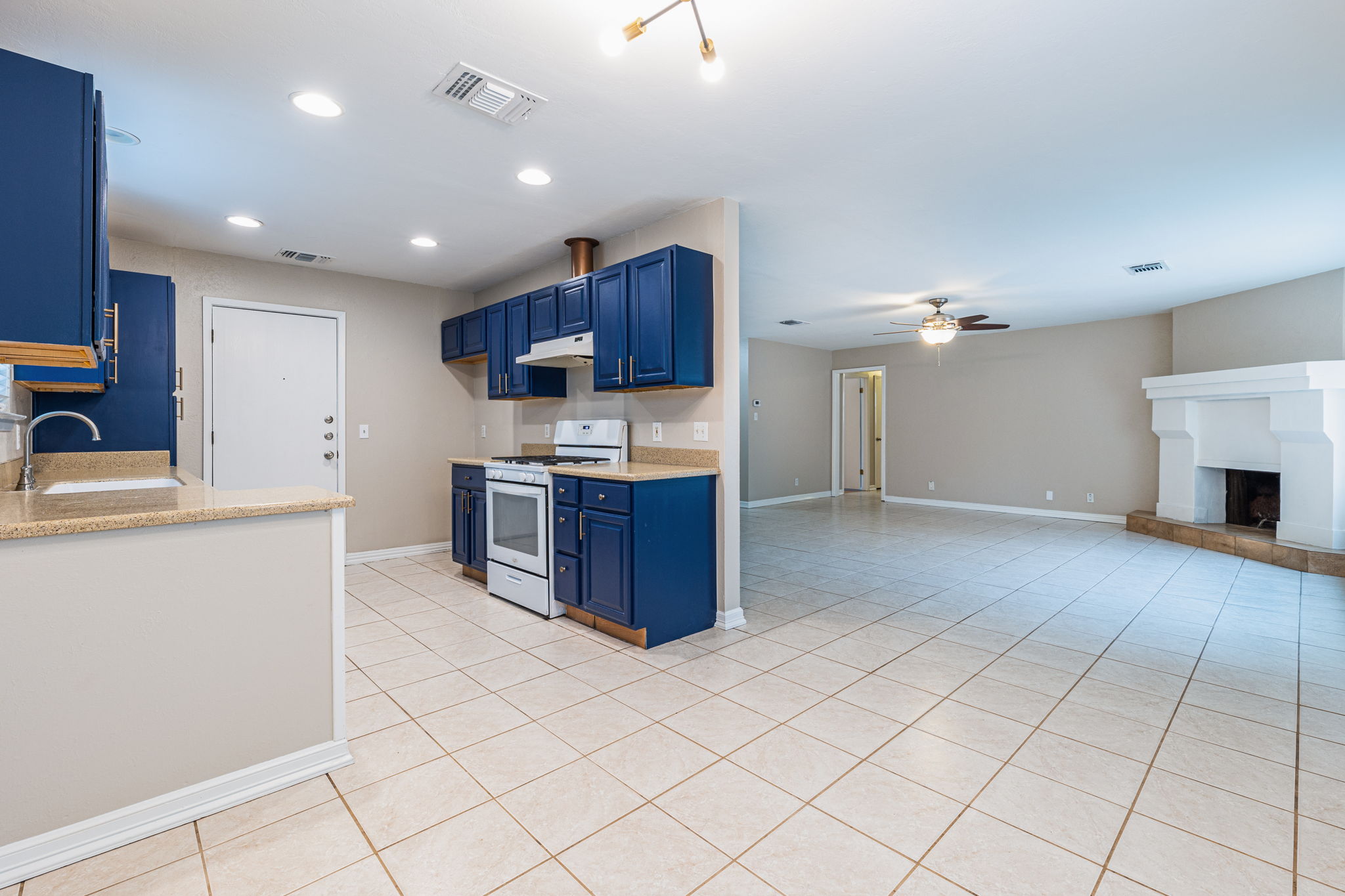 12914 Pegasus Street Austin, TX 78727 - Photo 30 of 30 Kitchen with blue cabinetry, white range with gas cooktop, light tile patterned flooring, open floor plan, and recessed lighting
