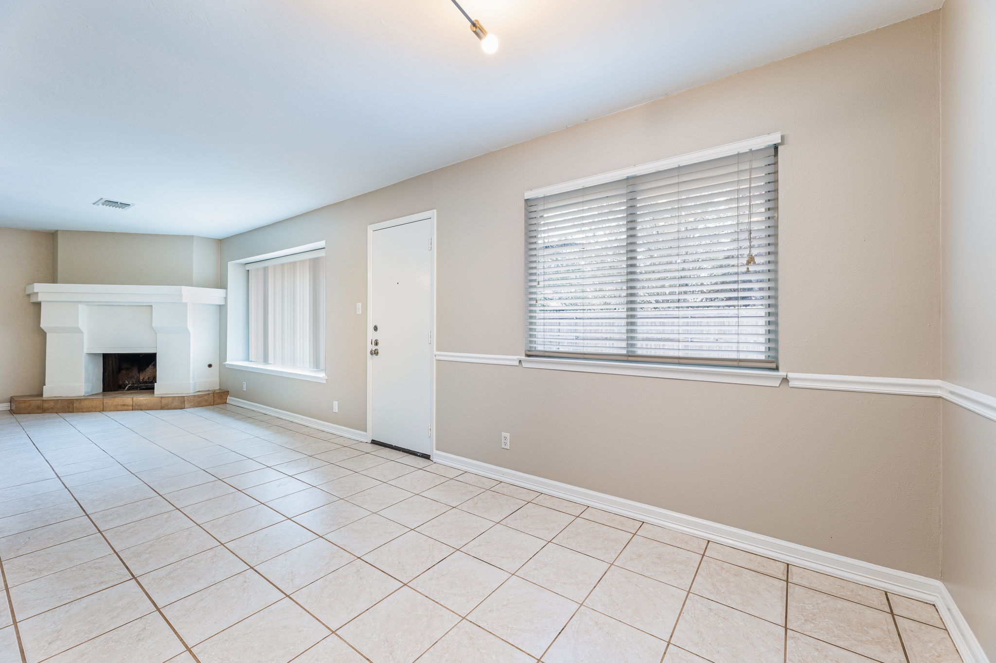 12914 Pegasus Street Austin, TX 78727 - Photo 9 of 30 Unfurnished living room featuring a fireplace with raised hearth and light tile patterned floors