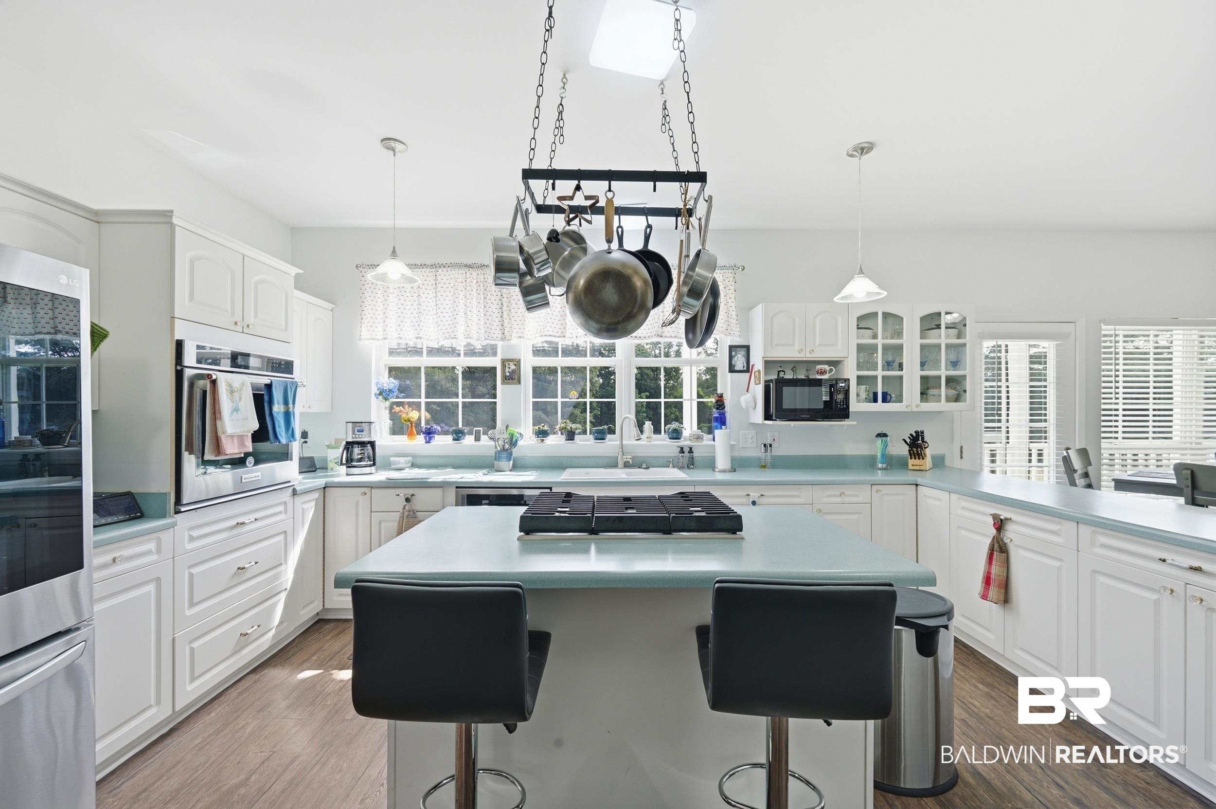 15855 Calvin Richerson Road Bay Minette, AL 36507 - Photo 22 of 83 Kitchen featuring an island with integrated cooktop, white cabinetry, light blue countertops, double wall ovens, and wood-finish flooring