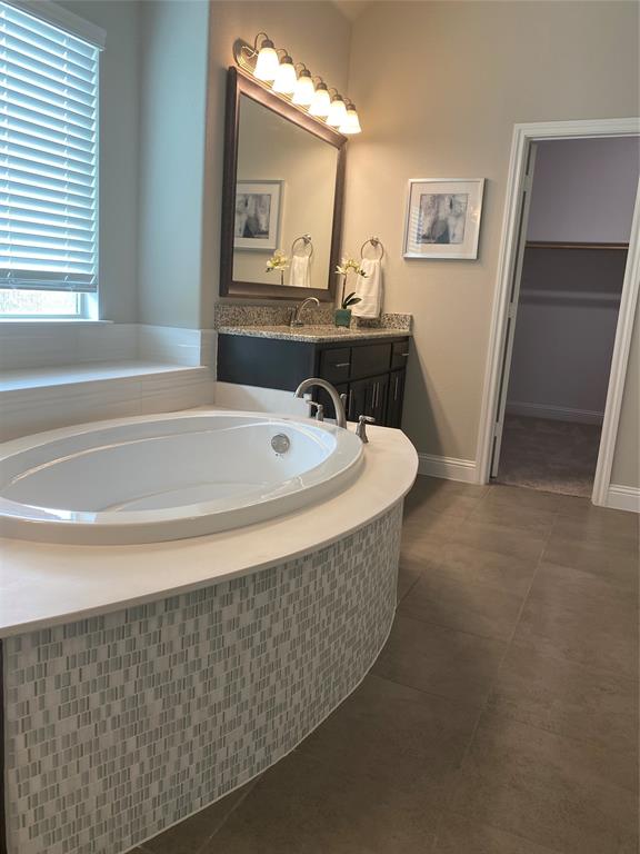 209 Johnson Street Granbury, TX 76048 - Photo 29 of 40 Bathroom featuring tiled tub, tile flooring, and vanity