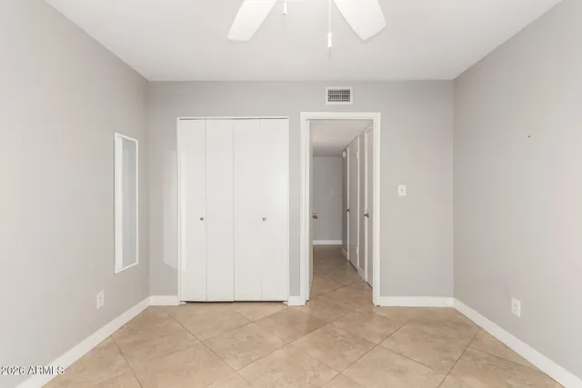 an empty room with chandelier fan and windows