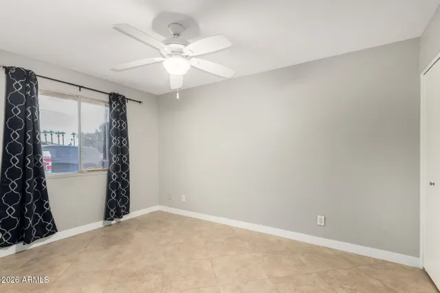 an empty room with a chandelier fan and closet