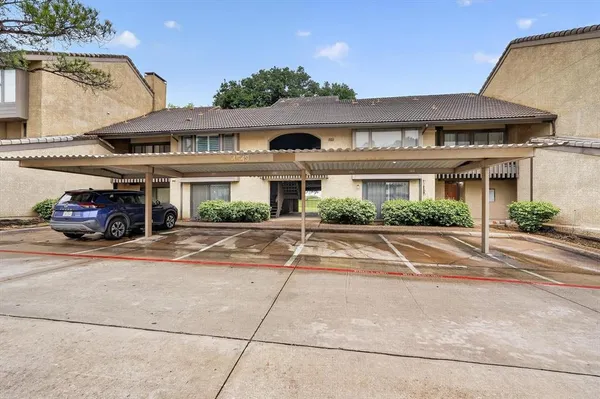 a front view of a building with cars parked
