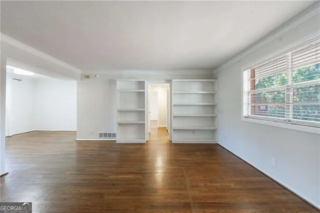 a view of an empty room with wooden floor and closet