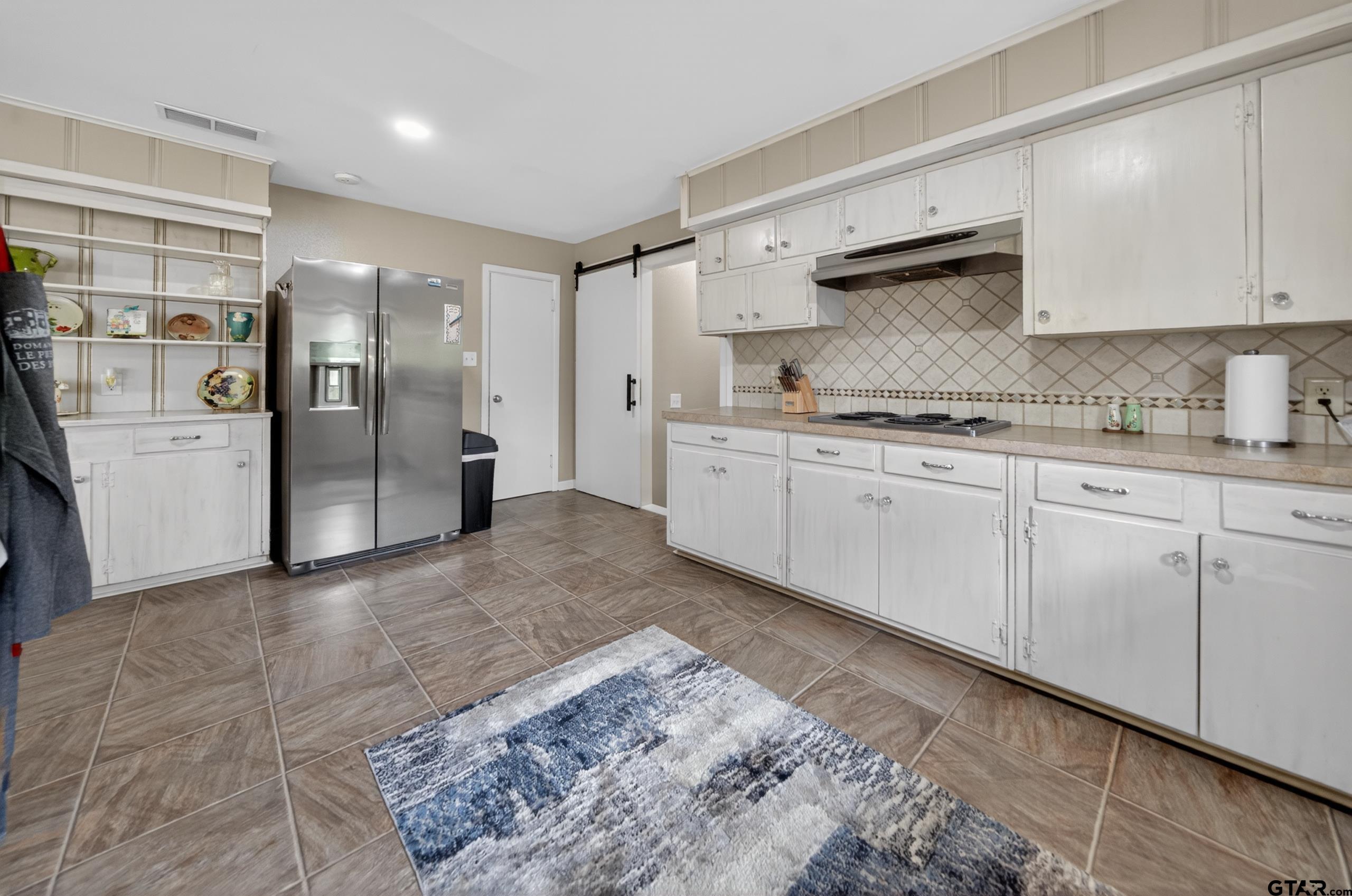 720 Wilma Street Tyler, TX 75701 - Photo 13 of 41 a kitchen with stainless steel appliances granite countertop a refrigerator a stove and white cabinets