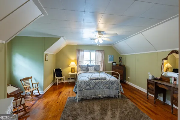 a spacious bedroom with a bed and wooden floor