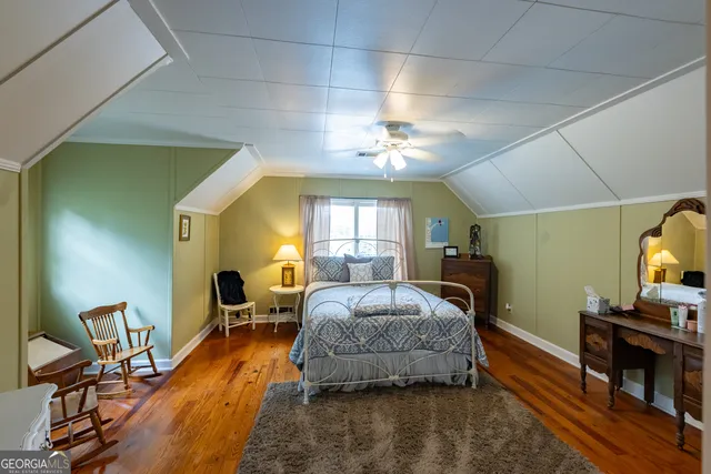 a spacious bedroom with a bed and wooden floor