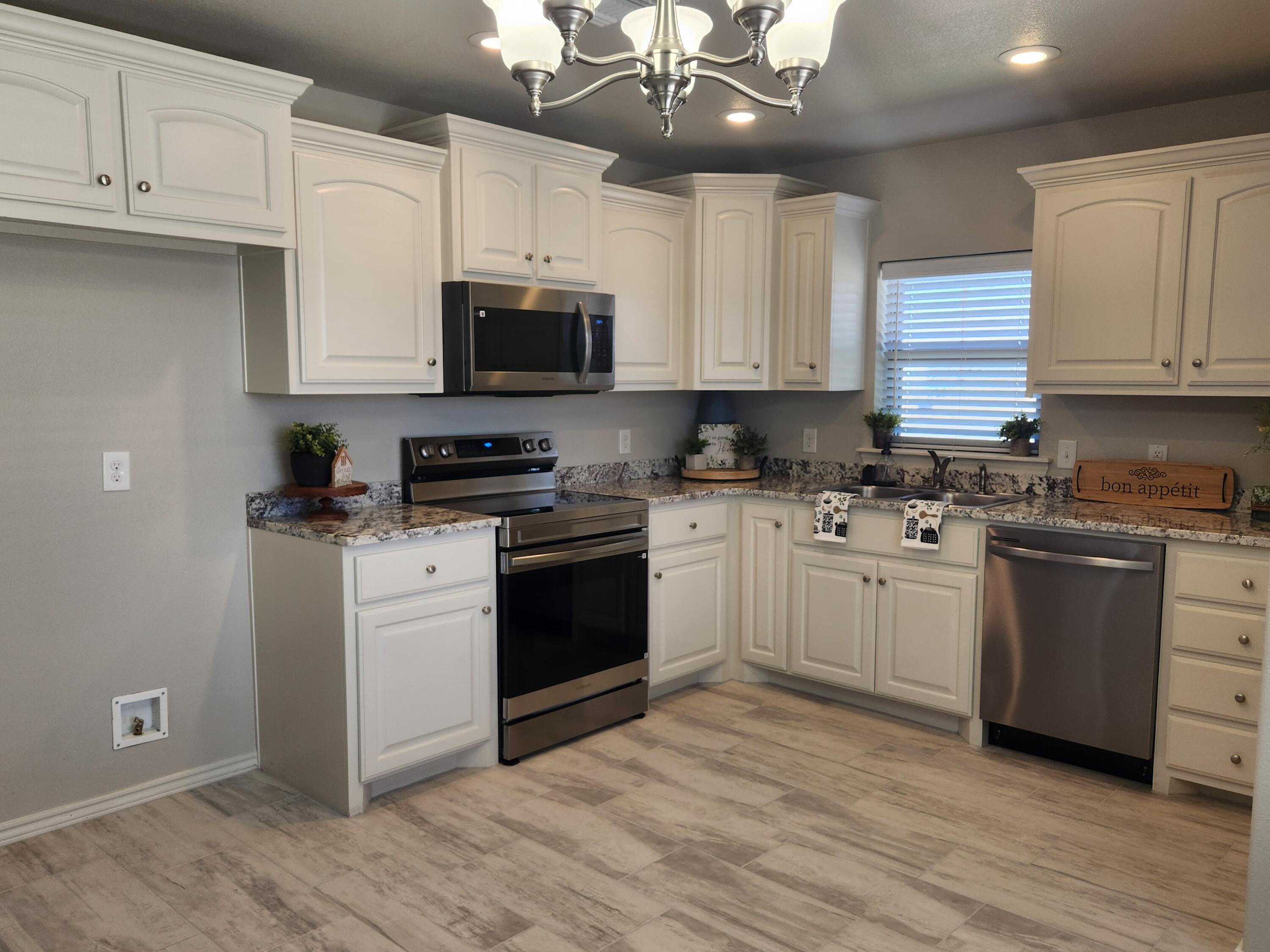8702 13th Street Lubbock, TX 79416 - Photo 3 of 25 a kitchen with granite countertop a sink stainless steel appliances and cabinets