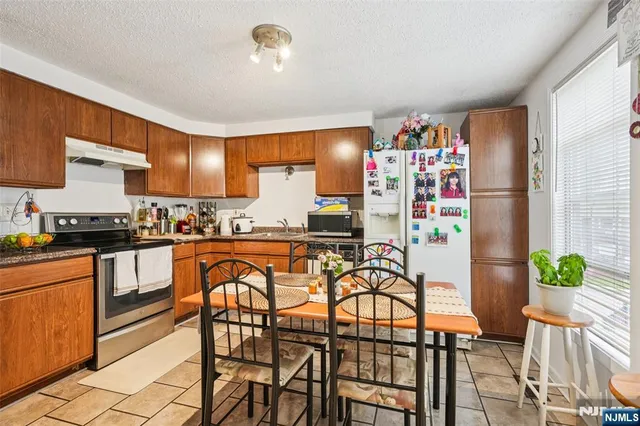 a kitchen with granite countertop lots of white furniture and stainless steel appliances