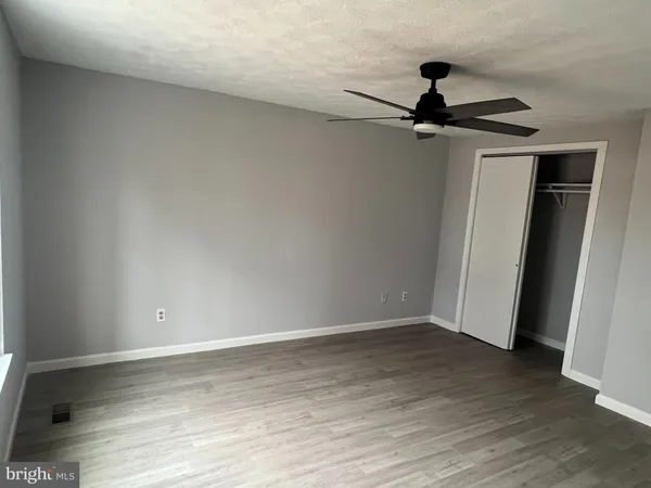 an empty room with wooden floor chandelier fan and windows