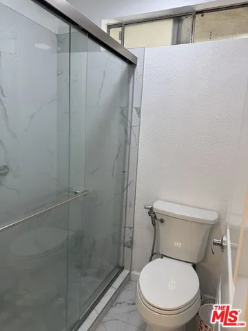 a white toilet sitting next to a shower