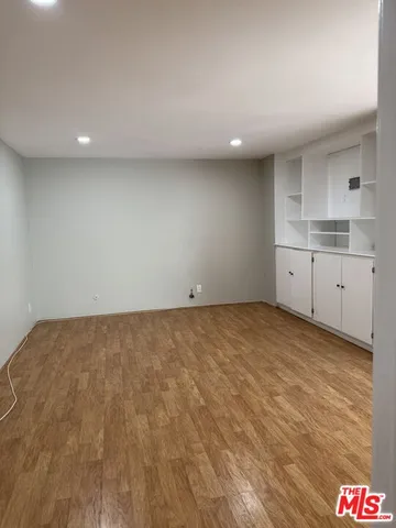 a view of an empty room and kitchen and window