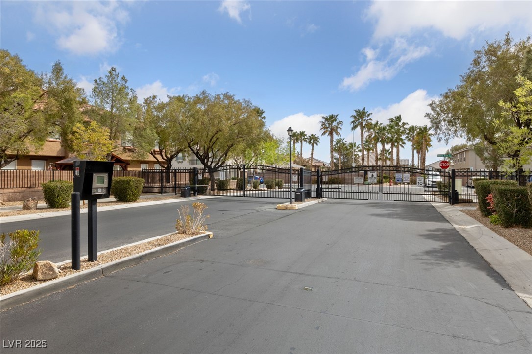 9121 Ripple Ridge Avenue, Unit 101 Las Vegas, NV 89149 - Photo 14 of 16 View of asphalt street featuring a gate, traffic signs, curbs, and a gated entry