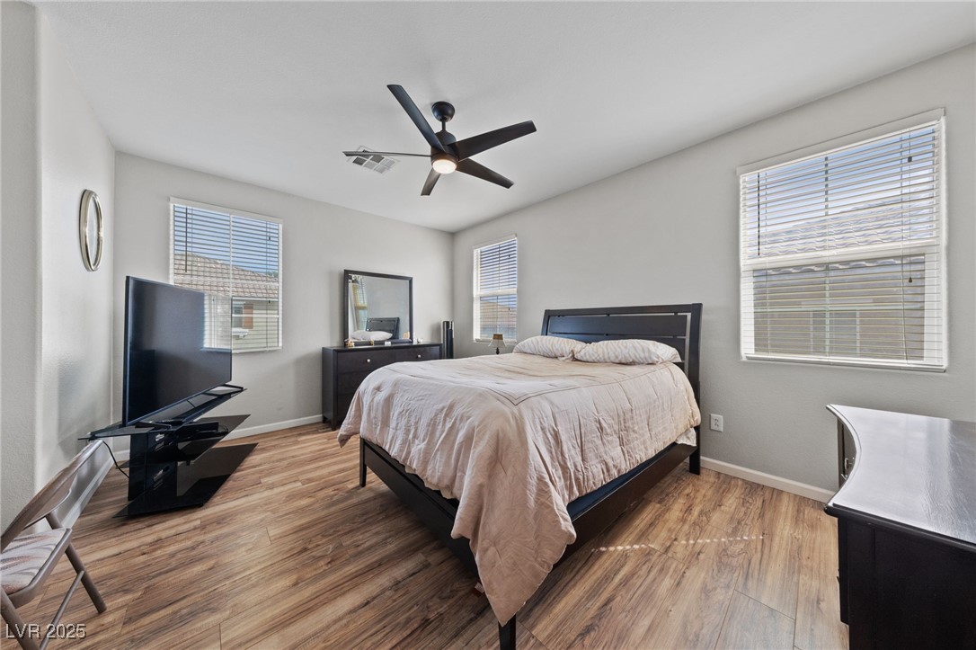 9121 Ripple Ridge Avenue, Unit 101 Las Vegas, NV 89149 - Photo 8 of 16 Bedroom featuring wood finished floors, multiple windows, and ceiling fan