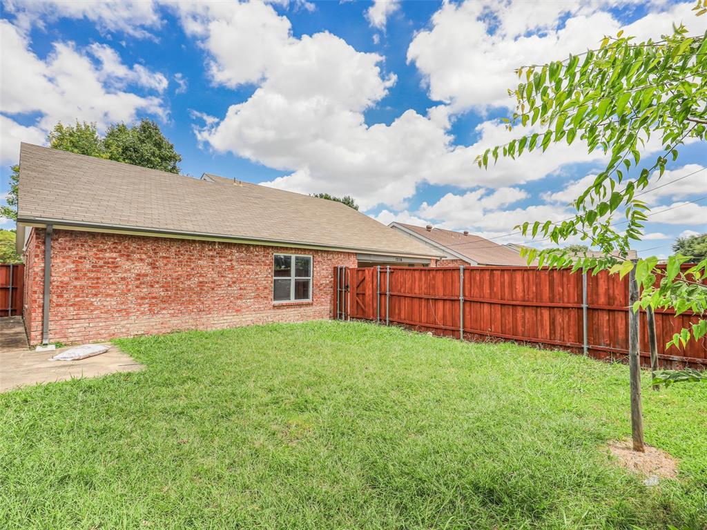1716 East Parker Road Plano, TX 75074 - Photo 25 of 25 Expansive backyard featuring a red-stained wooden privacy fence, mature trees, and an established lawn