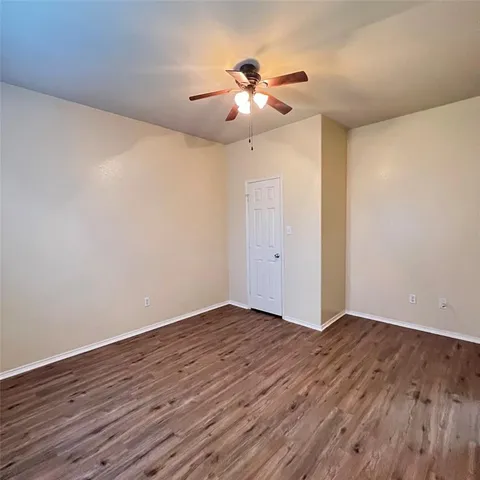 an empty room with wooden floor chandelier fan and windows