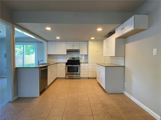 a large kitchen with a large counter top stainless steel appliances and cabinets