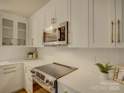 a kitchen with stainless steel appliances white cabinets and a stove top oven