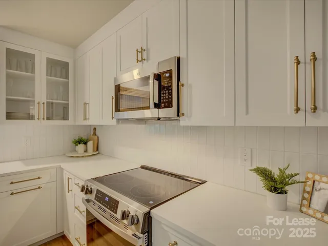 a kitchen with stainless steel appliances white cabinets and a stove top oven