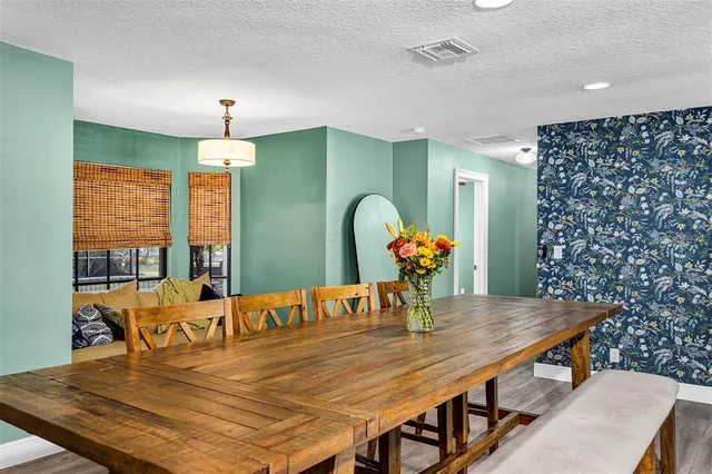 a outdoor kitchen with a dining table chairs and white cabinets