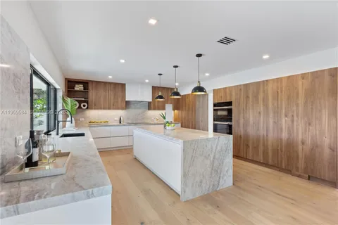 a large white kitchen with a large window and stainless steel appliances