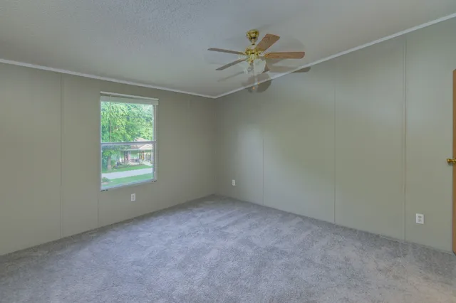 an empty room with a chandelier fan and windows