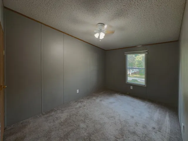 en empty room with windows and ceiling fan