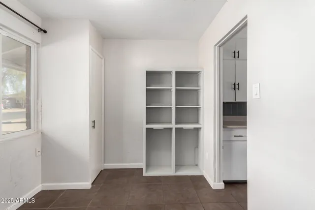 a view of a kitchen with refrigerator and an empty room