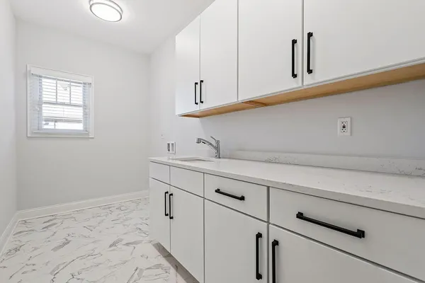 a kitchen with white cabinets and sink