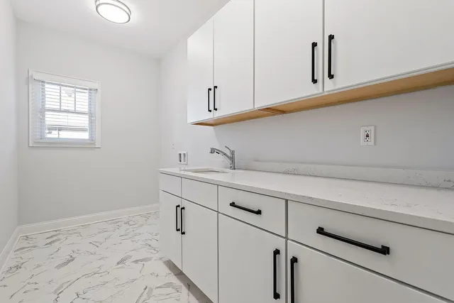 a kitchen with white cabinets and sink