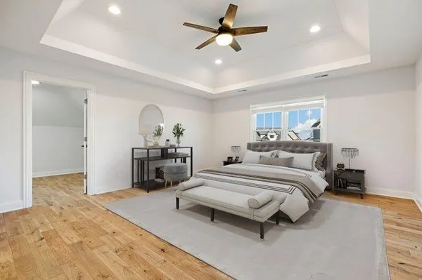 a spacious bedroom with a bed a dresser and flowerpot