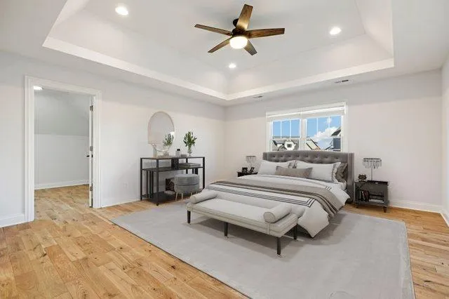 a spacious bedroom with a bed a dresser and flowerpot