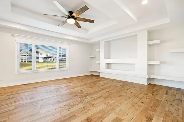 a view of an empty room with a window and wooden floor