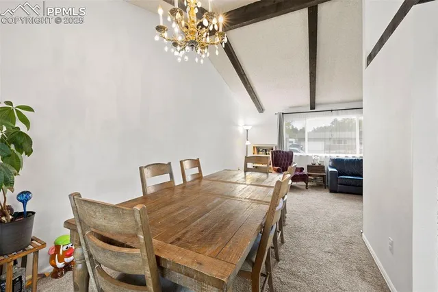 a view of a dining room with furniture a chandelier and a window