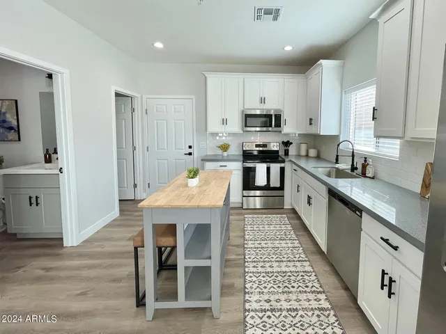 a kitchen with stainless steel appliances granite countertop a stove top oven a sink dishwasher and cabinets with wooden floor