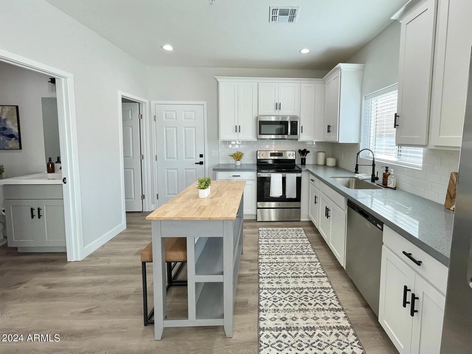 815 East Roma Avenue, Unit 5 Phoenix, AZ 85014 - Photo 5 of 28 a kitchen with stainless steel appliances granite countertop a stove top oven a sink dishwasher and cabinets with wooden floor