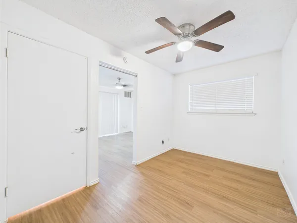 an empty room with wooden floor and ceiling fan
