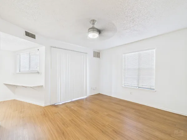 a view of empty room with wooden floor and fan