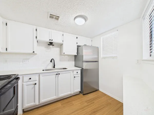 a kitchen with stainless steel appliances a sink cabinets and wooden floor