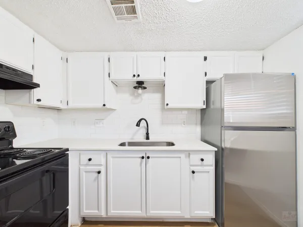 a kitchen with stainless steel appliances white cabinets and a refrigerator