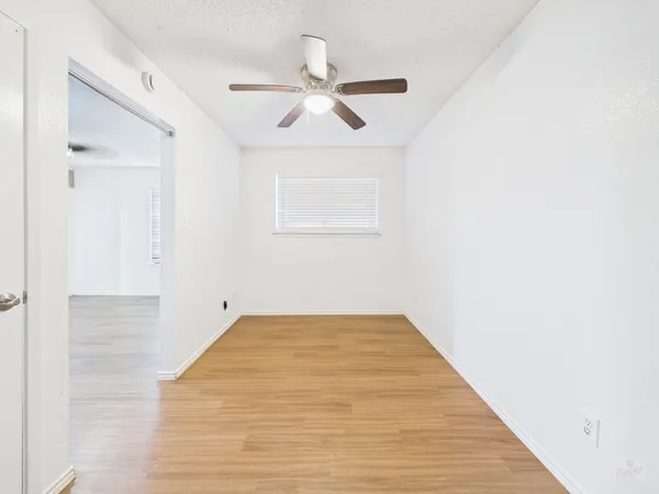 a view of a room with wooden floor and ceiling fan