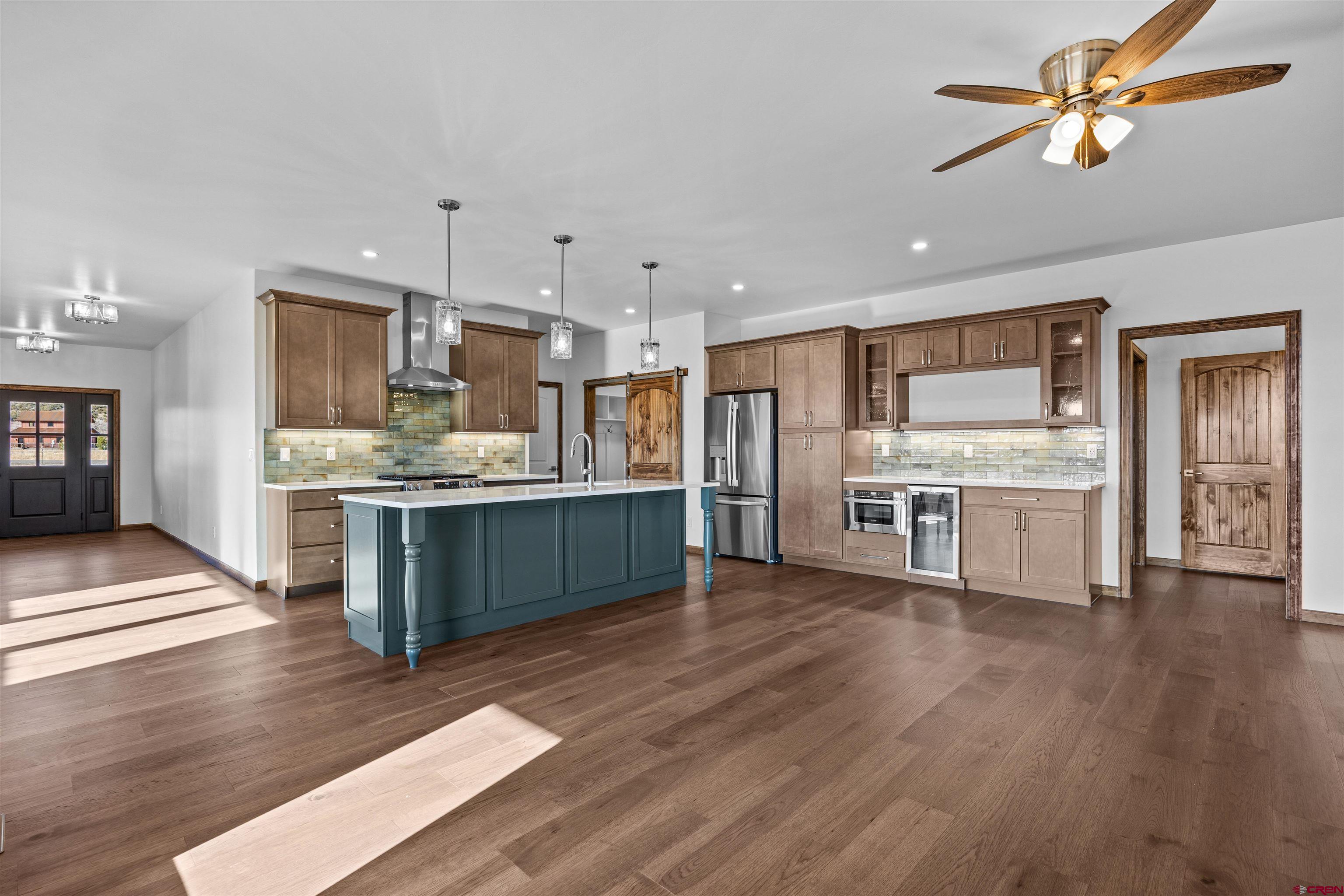 21470 Government Springs Road Montrose, CO 81403 - Photo 16 of 42 a kitchen with stainless steel appliances kitchen island granite countertop a refrigerator a stove a sink dishwasher and white cabinets with wooden floor