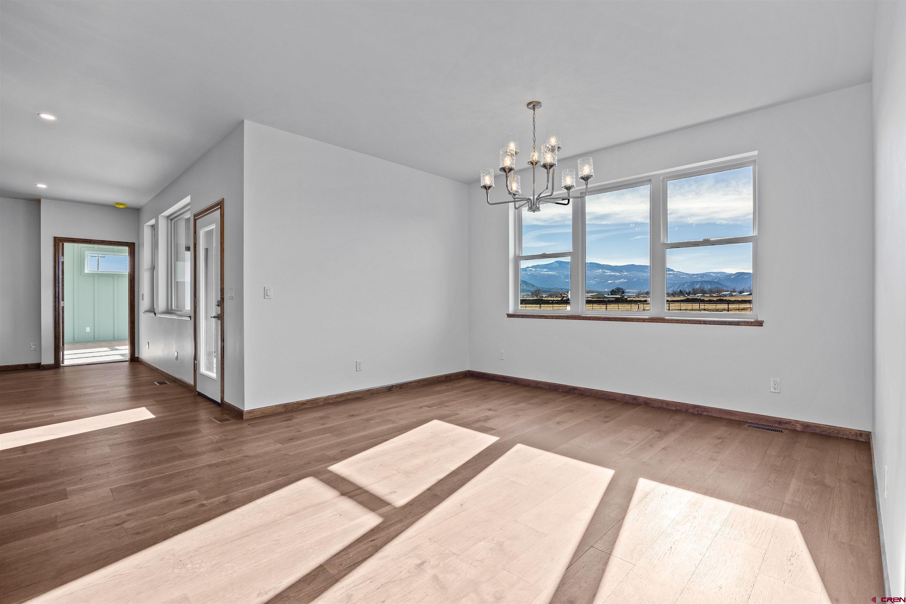 21470 Government Springs Road Montrose, CO 81403 - Photo 21 of 42 an empty room with wooden floor chandelier and windows