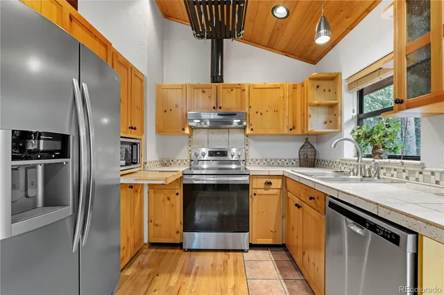 a kitchen with stainless steel appliances granite countertop a sink a stove and a refrigerator