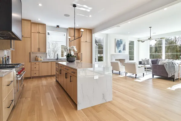 a kitchen with stainless steel appliances a stove a sink dishwasher a refrigerator white cabinets and wooden floor next to a window