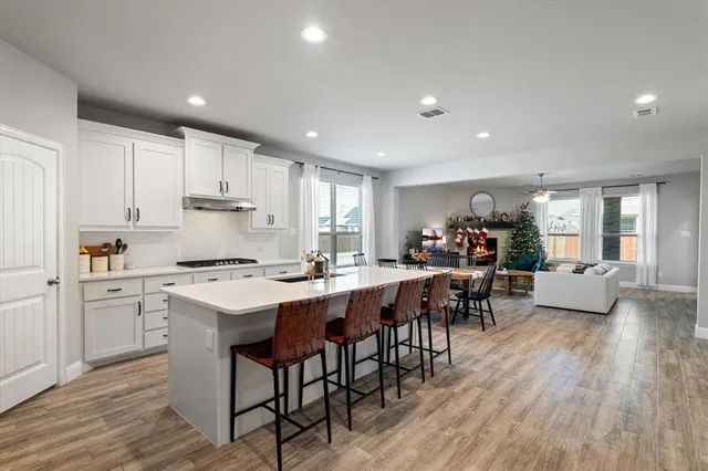 a kitchen with a dining table chairs wooden floor appliances and cabinets