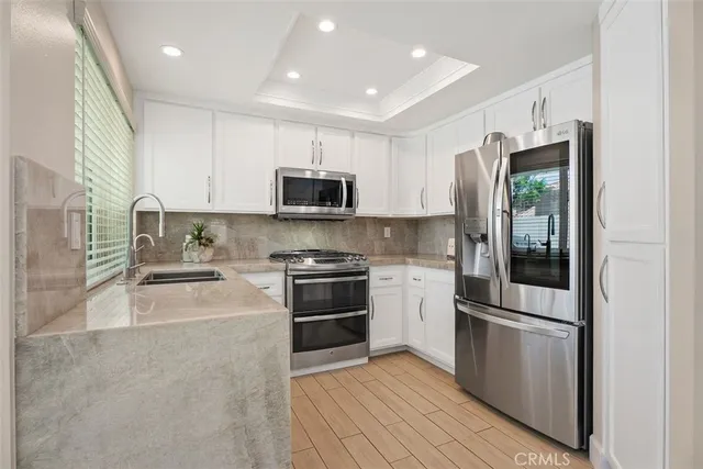 a kitchen with stainless steel appliances kitchen island granite countertop a refrigerator and a sink