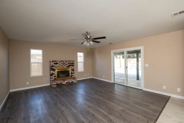 an empty room with windows and ceiling fan