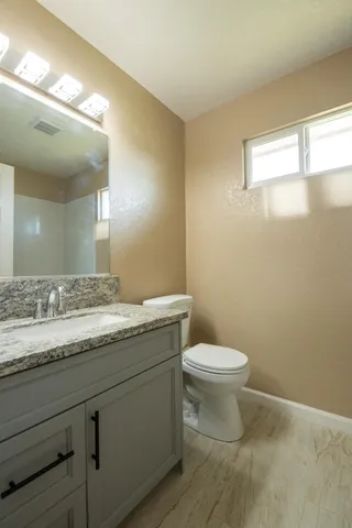 a bathroom with a granite countertop sink a toilet and a mirror